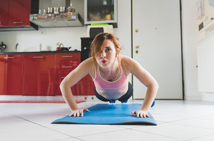 portrait-of-young-woman-doing-push-ups-on-kitchen-floor